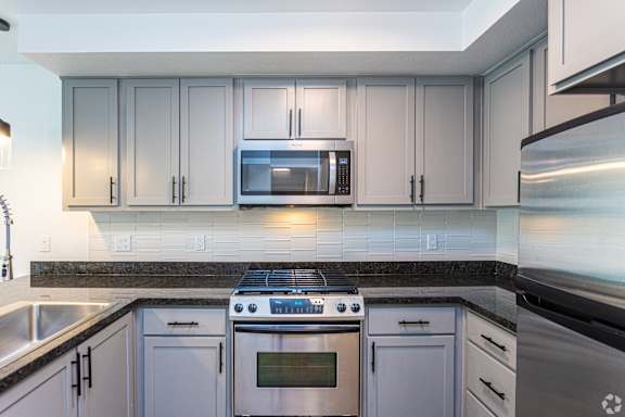 A modern kitchen with a stainless steel stove top oven, microwave, and fridge at 128 on State, Kirkland, WA, 98033