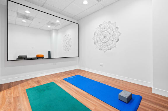 a yoga room with a large mirror and three yoga mats on the floor at Shoreham and Tides, Chicago