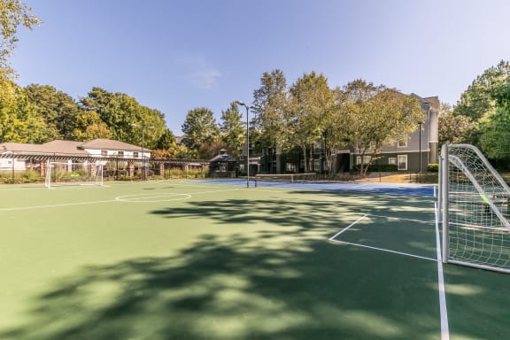 a tennis court with a net and a building in the background at Deerfield Village, Alpharetta, GA