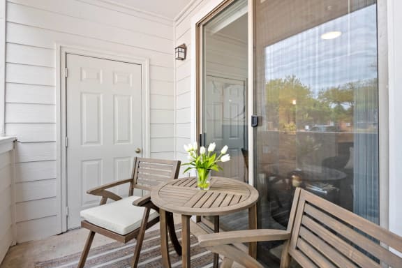 a small porch with a table and chairs and a sliding glass door at Mission Gate, Plano, 75024