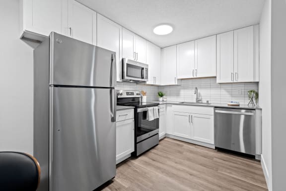an apartment kitchen with stainless steel appliances and white cabinets at Veranda La Mesa in La Mesa, 91942