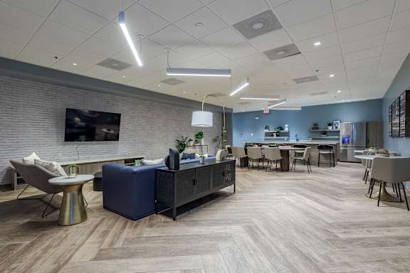 a living room with a tv and tables and chairs at The Citizen at Shirlington Village in Arlington, VA
