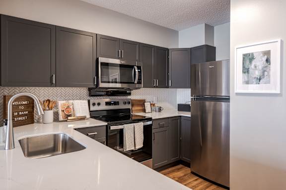 A kitchen with a stove, refrigerator, and microwave.