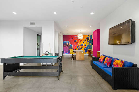 A pool table is in a room with a couch and a television.