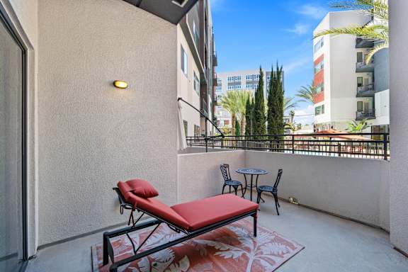A balcony with a red couch and a table.