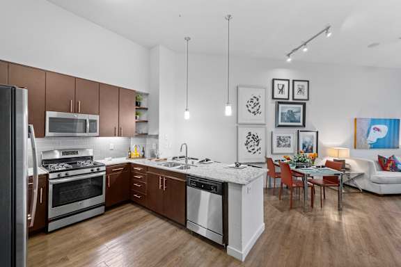 A modern kitchen with wooden floors and stainless steel appliances.