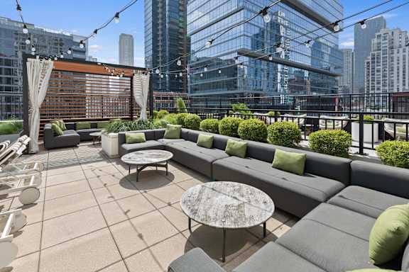 A patio with a couch, table and chairs with a cityscape in the background.