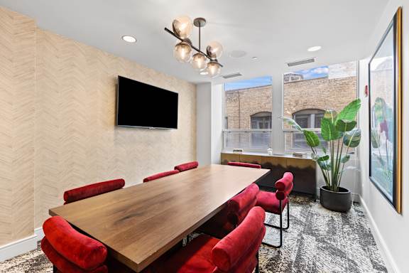 A conference room with a long table and red chairs.