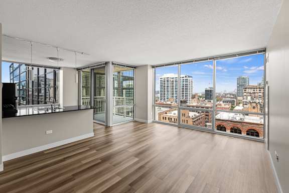 A room with wooden floors and a view of the city through large windows.
