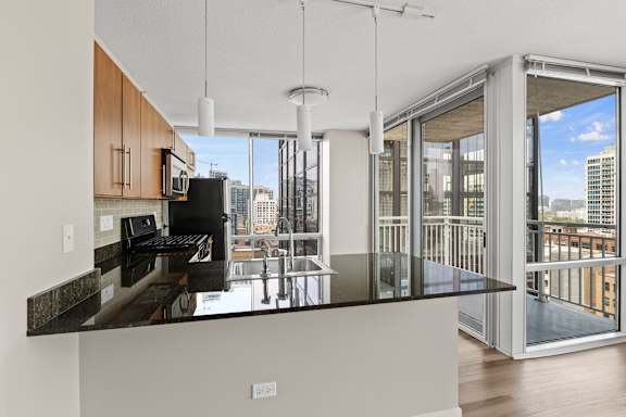 A modern kitchen with a black countertop and a view of the city.