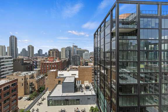 A modern glass building stands in front of a city skyline.