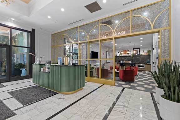 A reception area with a green counter and a gold framed glass door.