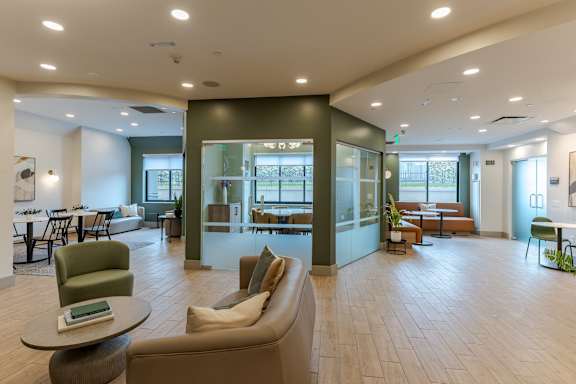A modern living room with a green chair and a brown sofa.