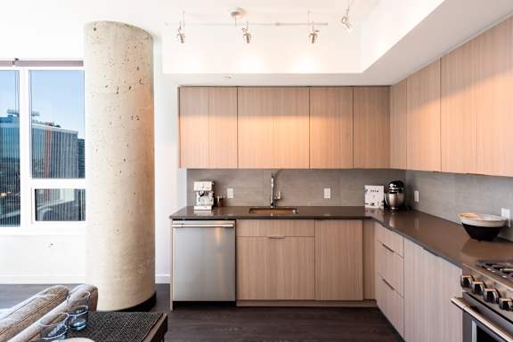 A modern kitchen with wooden cabinets and a large window.