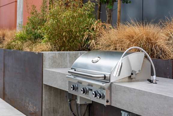 A silver grill is on a concrete surface.