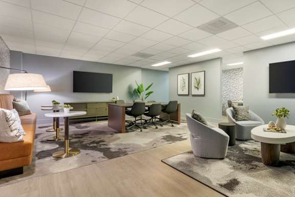 A modern business center with a variety of seating options and a flat screen TV mounted on the wall at The Vue in San Pedro, CA