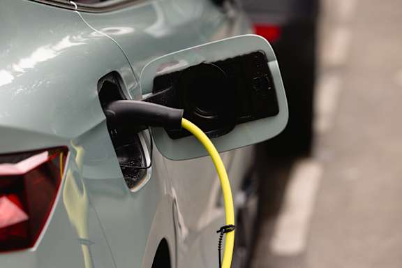 A car is being charged with a yellow cable plugged into the back of it at 128 on State Apartments in Kirkland, WA
