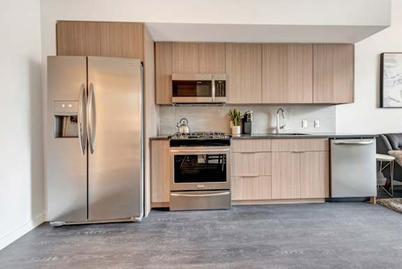 A modern kitchen with a stainless steel refrigerator and wooden cabinets.