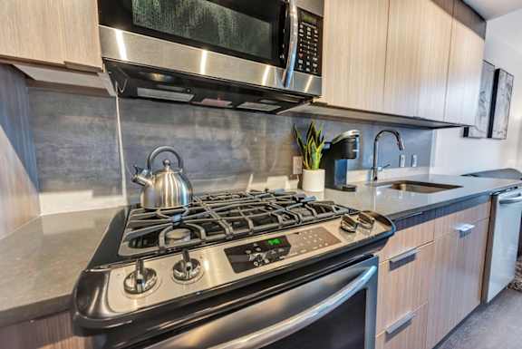 A modern kitchen with a stainless steel stove and a microwave above it.