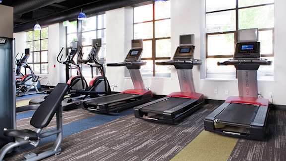 A gym with treadmills, elliptical machines, and stationary bikes at Skye at Belltown Apartments, Seattle, 98121