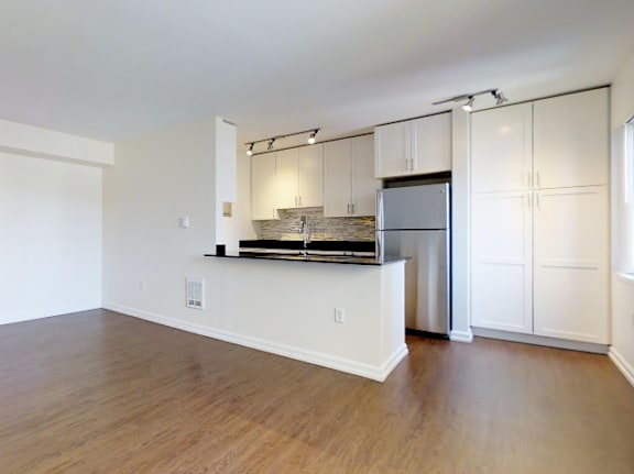 A kitchen with white cabinets and a refrigerator at Skye at Belltown Apartments, Washington 98121