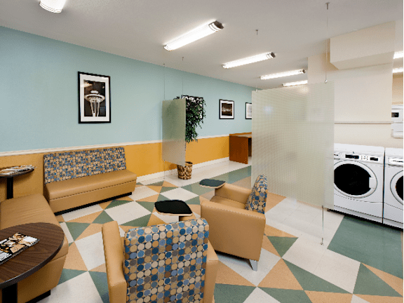 A laundry room with a washer and dryer and a couch at Skye at Belltown Apartments, Seattle, 98121