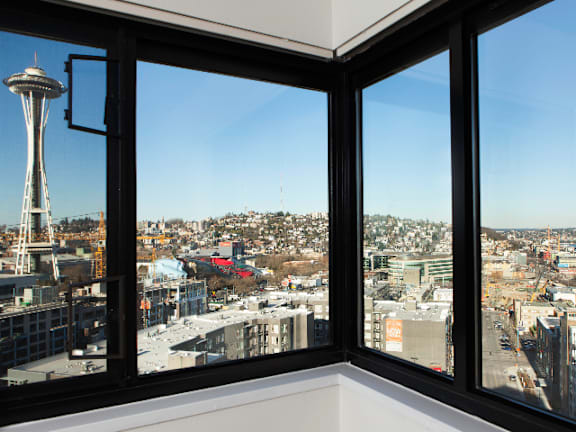 A view of a cityscape from a window with the Space Needle visible in the distance at Skye at Belltown Apartments, Washington 98121