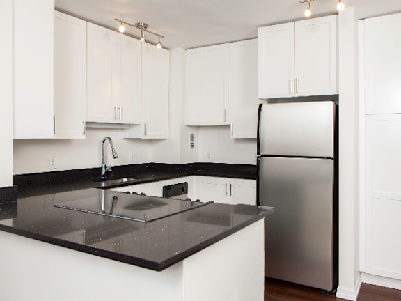 A kitchen with white cabinets and a black counter top at Skye at Belltown Apartments, Washington