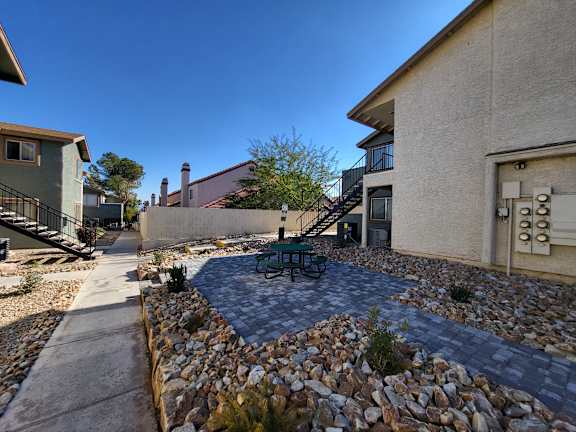 A patio with a table and chairs is surrounded by a rock wall.