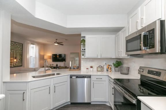 A modern kitchen with white cabinets and stainless steel appliances at Deerfield Village, Alpharetta, GA