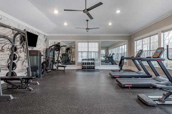 A spacious gym with treadmills, elliptical machines, and a television.