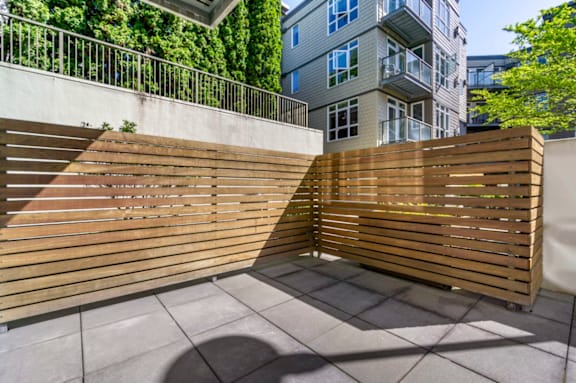 A wooden fence divides a concrete walkway.