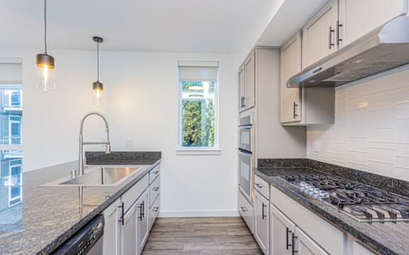 A modern kitchen with a granite countertop and stainless steel appliances.