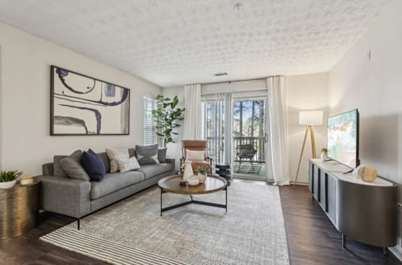 A living room with a grey couch, a coffee table, and a painting on the wall.