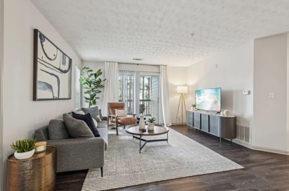 A living room with a grey couch, a coffee table, and a painting on the wall.