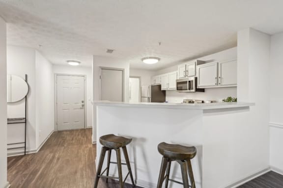 A kitchen with white walls and wooden floors.