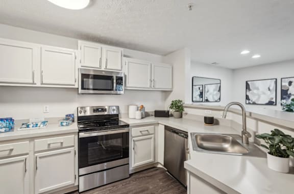 A white kitchen with a stove, oven, and microwave.