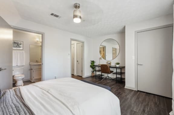 A bedroom with a large bed and a desk with a chair.