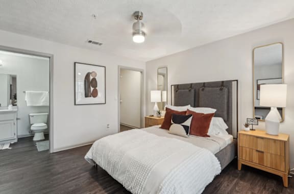 A bedroom with a large bed, a dresser, and a mirror.