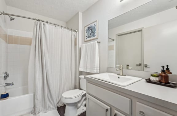 A white bathroom with a toilet, sink, and shower.