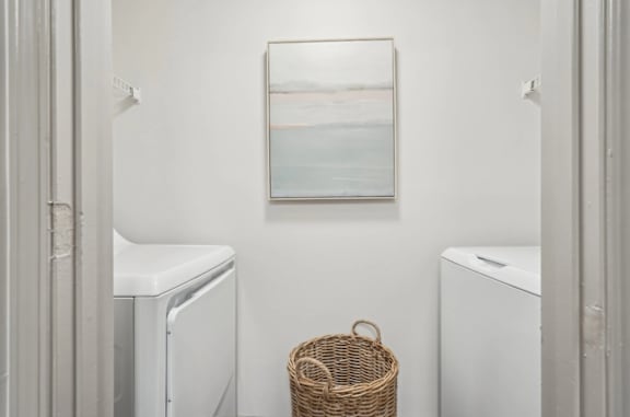 A laundry room with a basket and a picture on the wall.