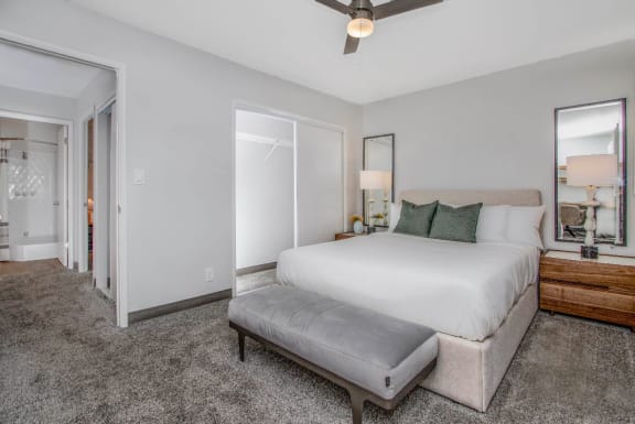 a spacious bedroom with a large bed, sitting bench, plush carpet, and a ceiling fan at Mala Grove, HI