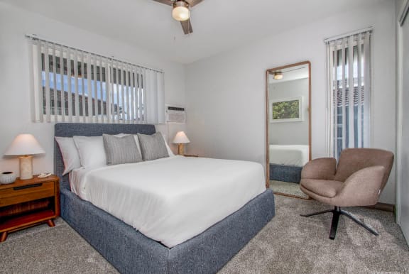 Cozy bedroom with a large bed, plush carpeting, and an accent chair at Mala Grove in Waipahu, HI 96797