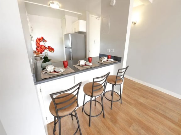 a kitchen and dining area with a breakfast bar and a stainless steel refrigerator at Waikele Towers in Waipahu, HI