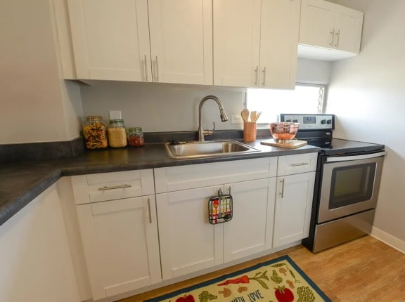 a white kitchen with marble counter tops and white cabinets at Waikele Towers Apartments, Waipahu, HI