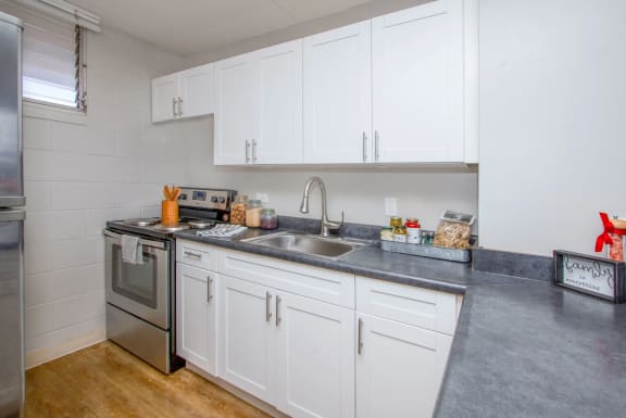 a kitchen with white cabinets and stainless steel appliances and a sink at Waikele Towers, Waipahu
