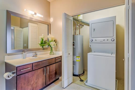 a bathroom with a washer and dryer next to a sink and a mirror at Avant at the Arboretum, Illinois, 60532