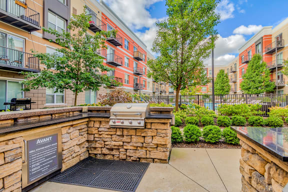 Outdoor kitchen patio area with grill and trees at Avant at the Arboretum, Illinois