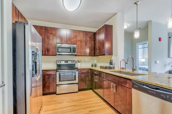 a kitchen with wooden cabinets and stainless steel appliances at Avant at the Arboretum, Illinois