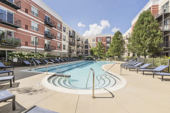 a swimming pool in front of a building with trees at Avant at the Arboretum, Lisle, IL